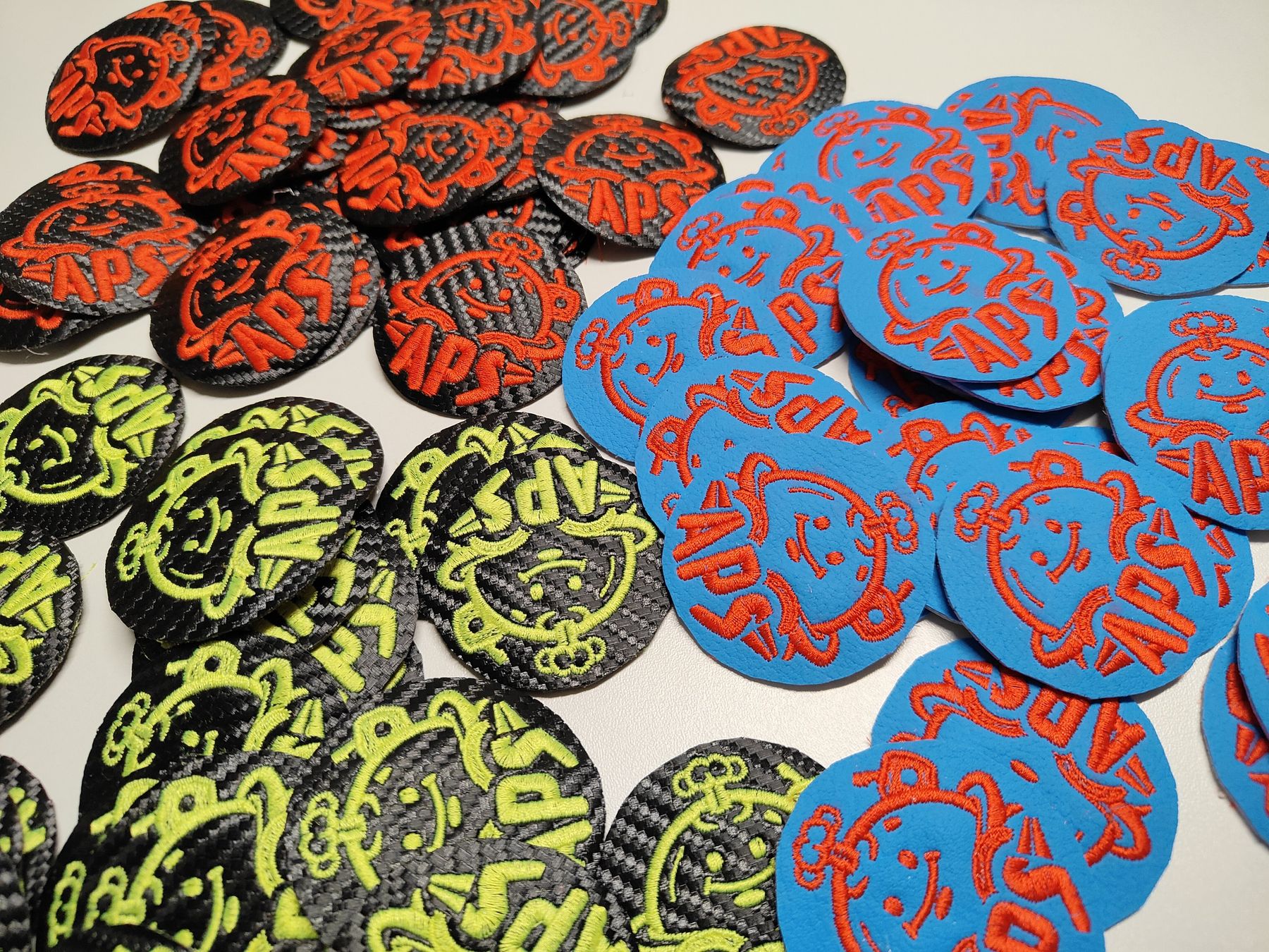 Losse geborduurde emblemen in rood, blauw en limegroen op de werktafel Losse geborduurde emblemen in rood, blauw en limegroen op de werktafel