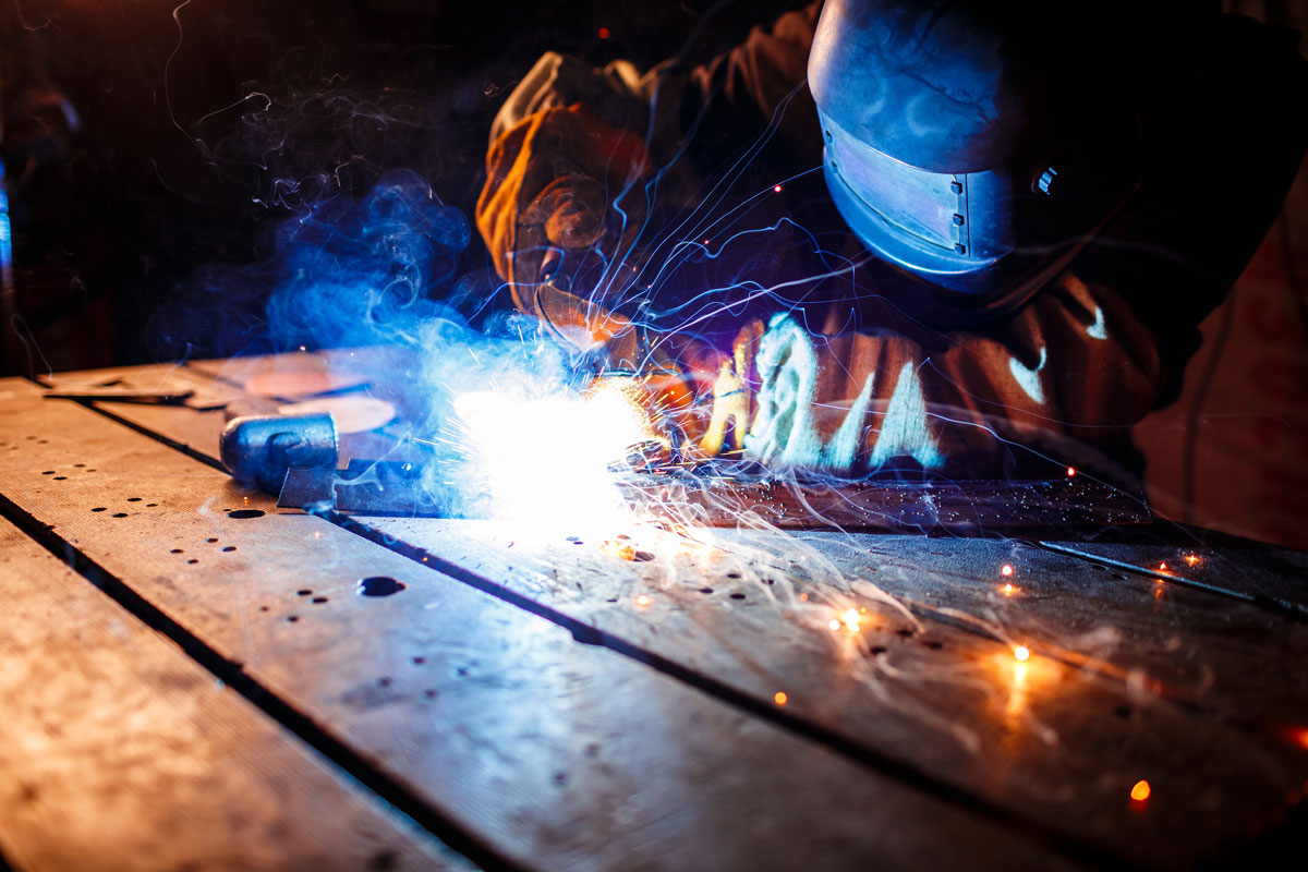 Lasser aan het werk aan een stalen constructie, vonken springen op Lasser aan het werk aan een stalen constructie, vonken springen op